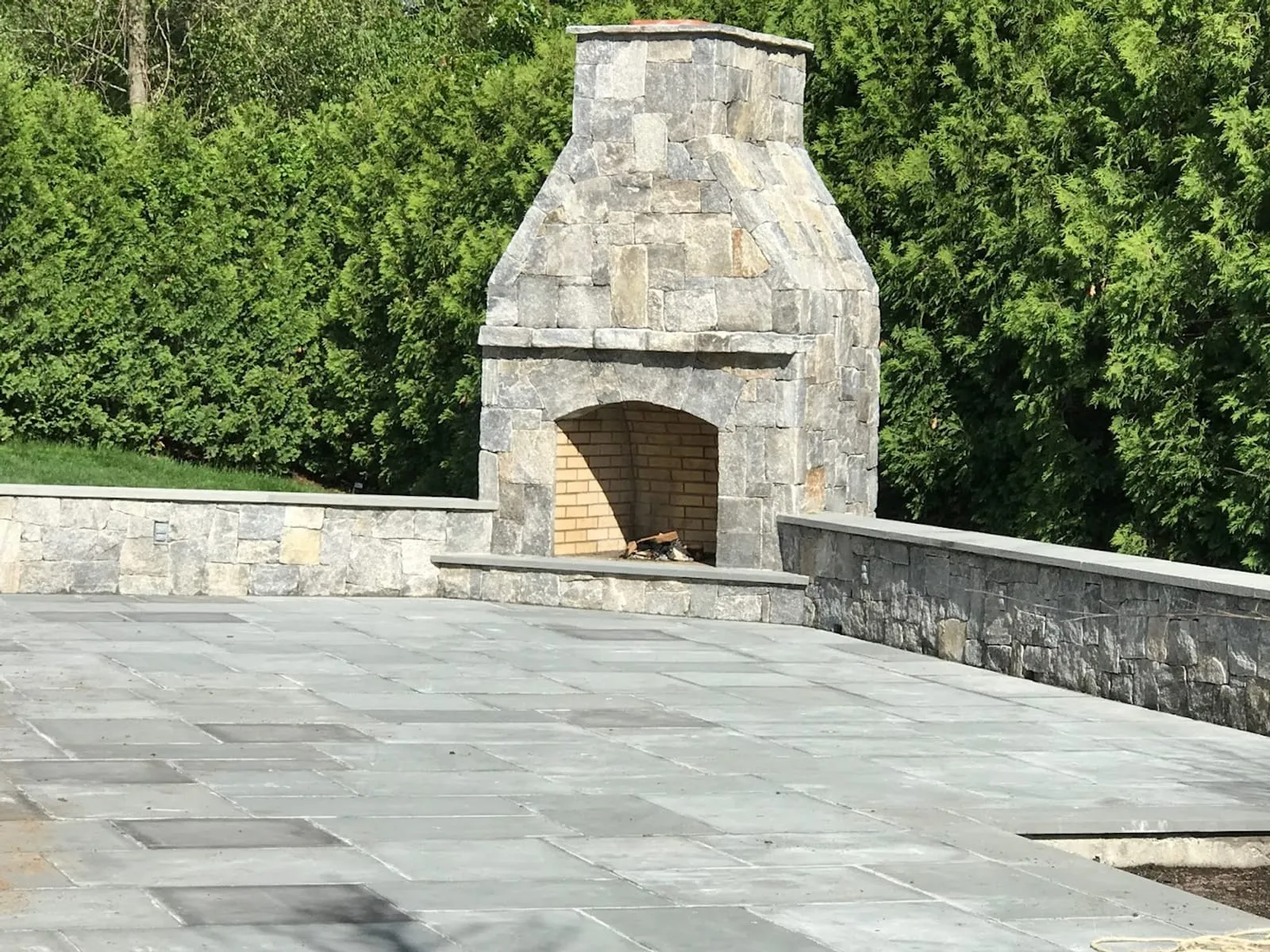 Custom natural stone outdoor fireplace and retaining wall with a bluestone patio — MRO Landscaping project