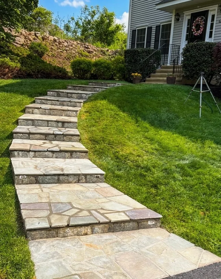 Natural flagstone steps and walkway climbing a hillside lawn to a front entry